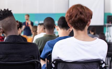trois élèves de dos qui écoutent leur enseignant
